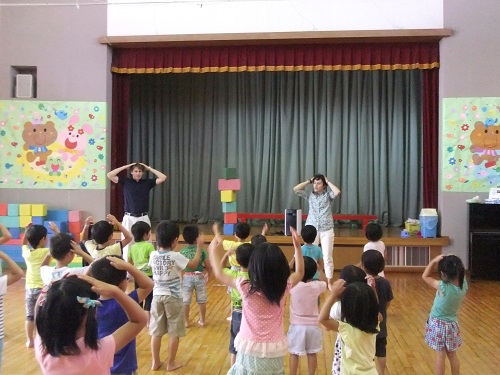 保育士と園児が一緒に体操している写真