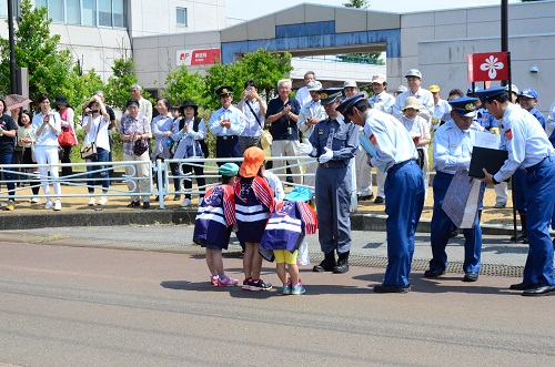 郵便局前で消防の人に表彰される子どもの写真